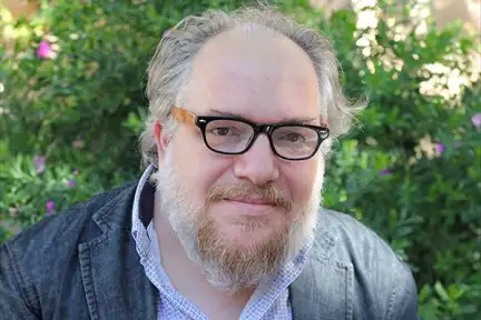 Une photographie de Mathias Énard, portant des lunettes de vue noires, face à l'objectif.