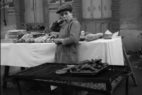 Un enfant travaille à la buvette du match et s'occupe des saucisses.