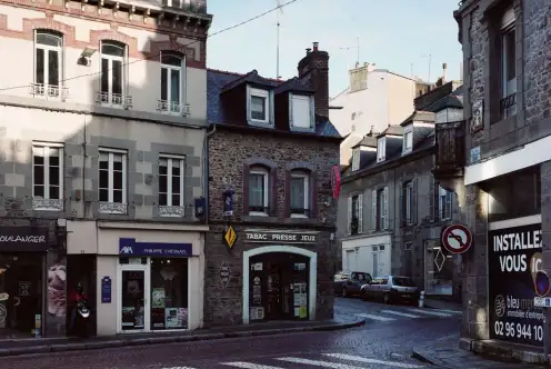 Une rue entre ombre et lumière, au pavés mouillés. Une vitrine de tabac, une autre d'assurance, ainsi