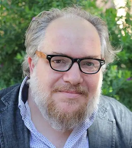 Une photographie de Mathias Énard, portant des lunettes de vue noires, face à l'objectif.