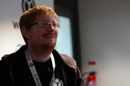 Une photographie de Nicolas Vigneron souriant, avec un tour de cou Wikisource.