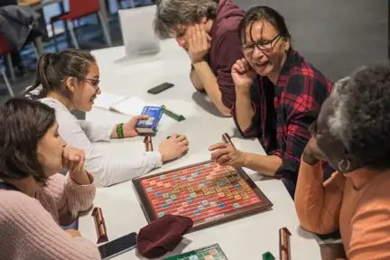 Une photographie d'un RDV 4C dans l'espace Vie du Citoyen des Champs Libres. Un groupe de personnes joue au Scrabble.