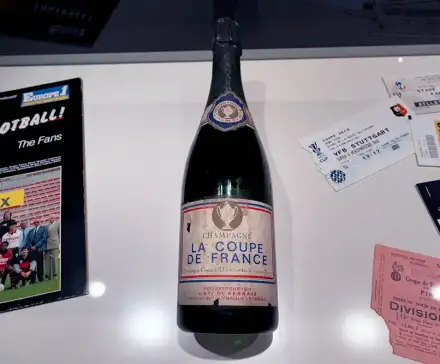 Une photo d'une bouteille de champagne marquée de l'inscription "La coupe de France", et d'autre objets en lien avec le football